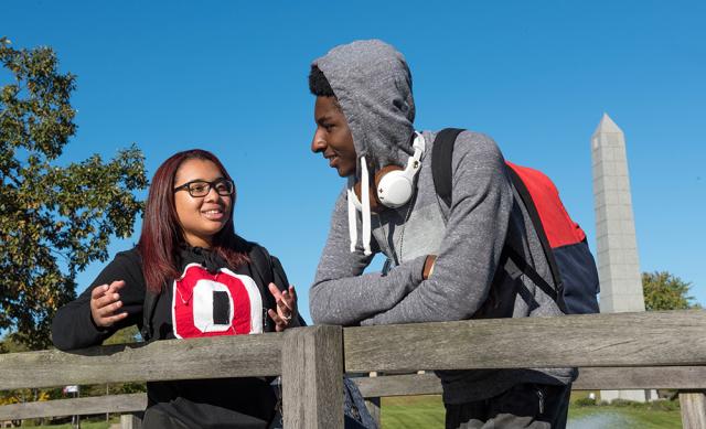Two Ohio State students talking by the fence in the grove.