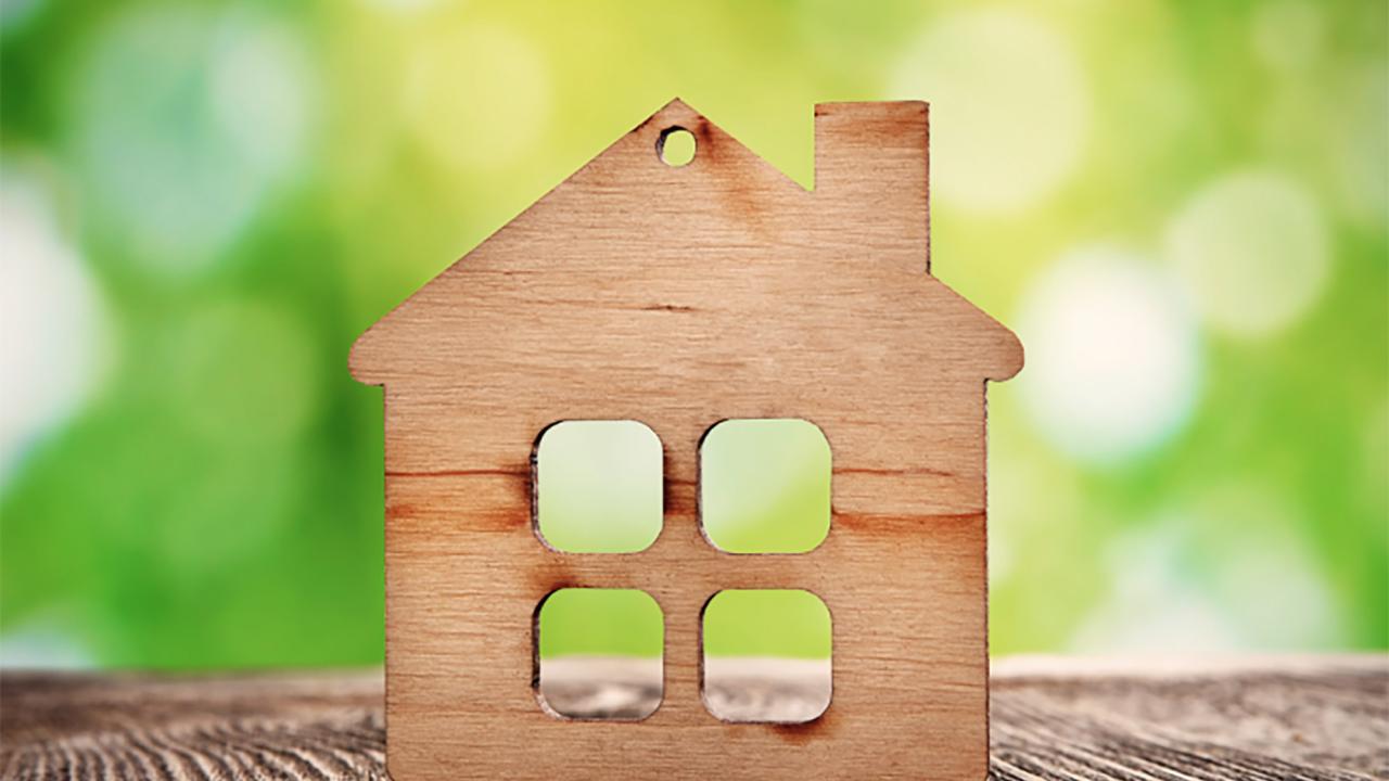 A small wooden house in front of blurred green leaves background